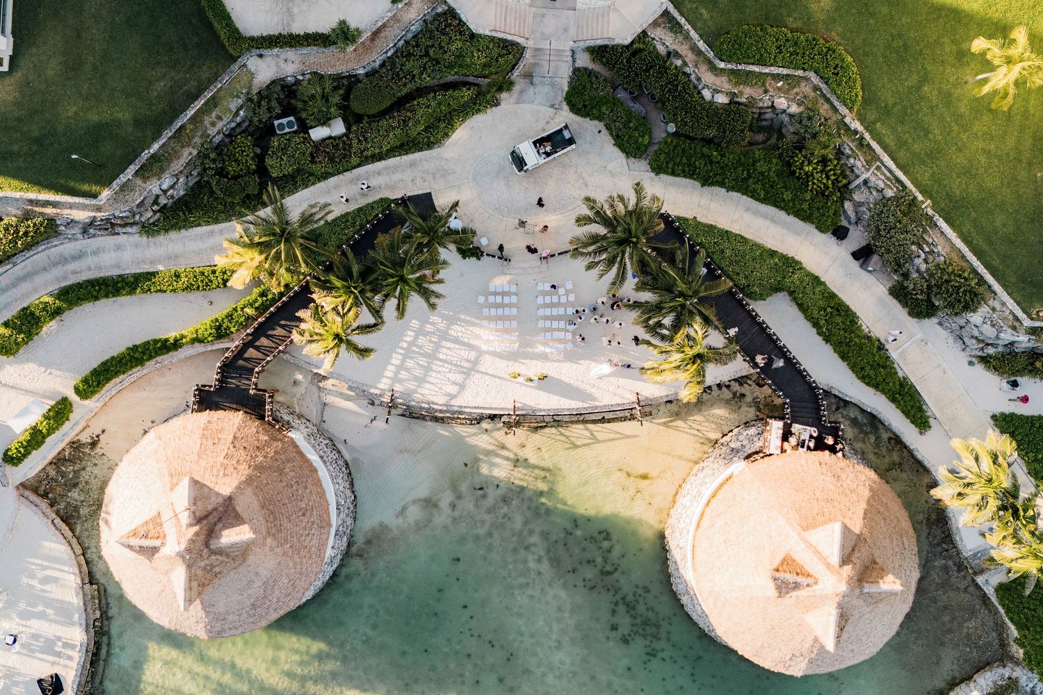 Aerial view of a tropical resort featuring palm trees, thatched umbrellas, and a lagoon pool. Hard Rock Riviera Maya wedding photographer