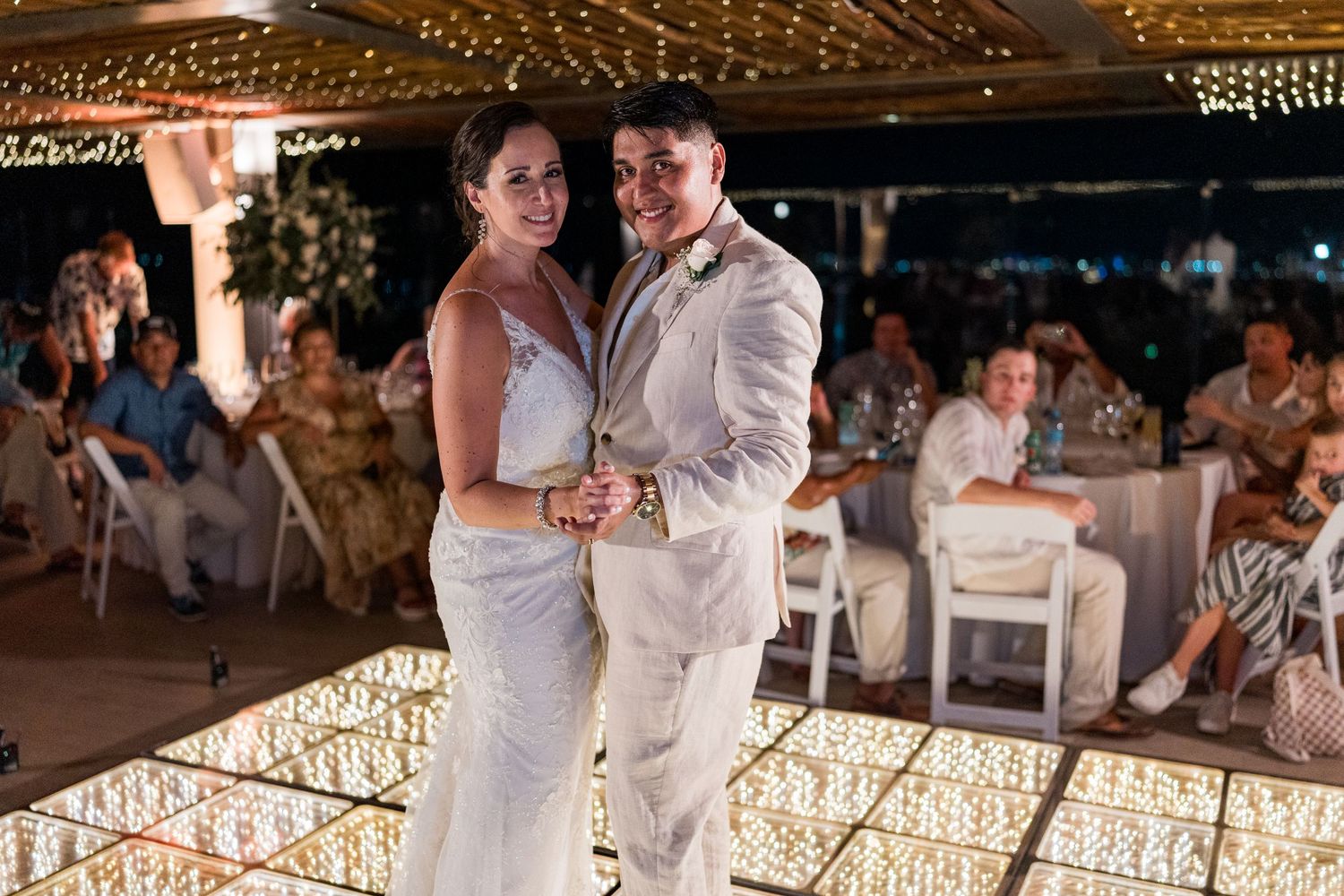 Bride and groom pose together on a glowing LED dance floor at their elegant wedding reception.
