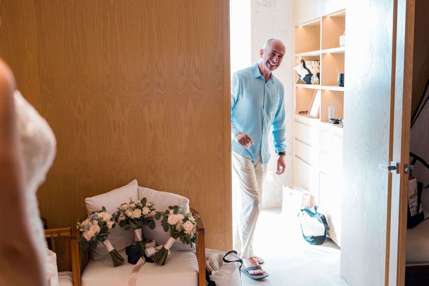 Father smiles seeing bride in wedding dress during emotional first look moment.