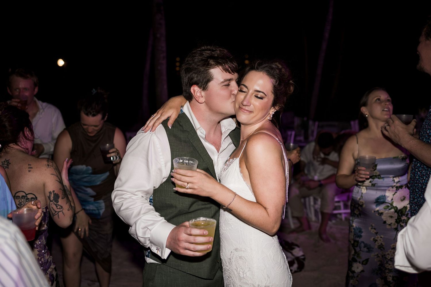 Bride and groom share a romantic kiss while dancing at their outdoor evening wedding reception.
