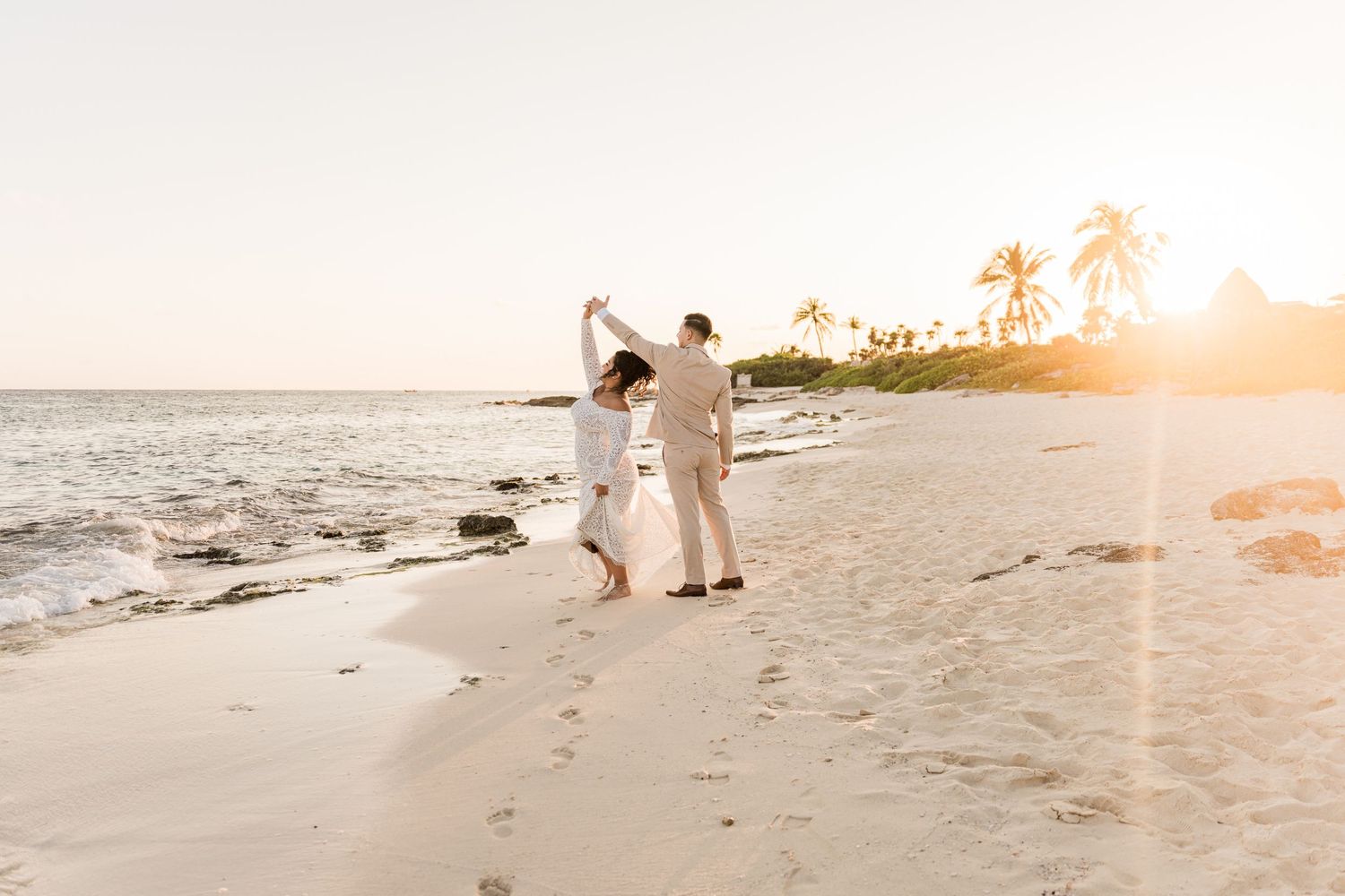 Xcaret Arte Wedding -Couple dancing on a tropical beach at golden sunset with palm trees and white sand.