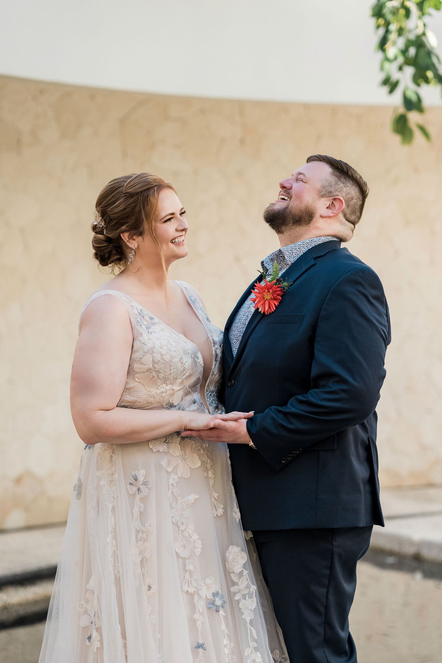 Secrets Akumal Wedding - A joyful bride and groom hold hands and laugh together outdoors, she in a floral gown