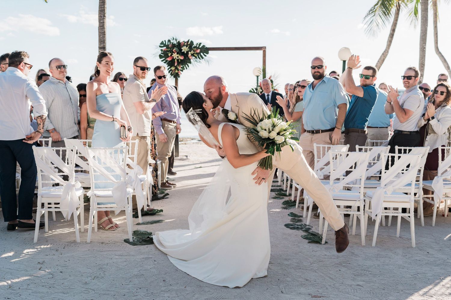 Barcelo Maya Grand Resort Wedding - Bride and groom share romantic dip kiss at outdoor beach wedding ceremony.
