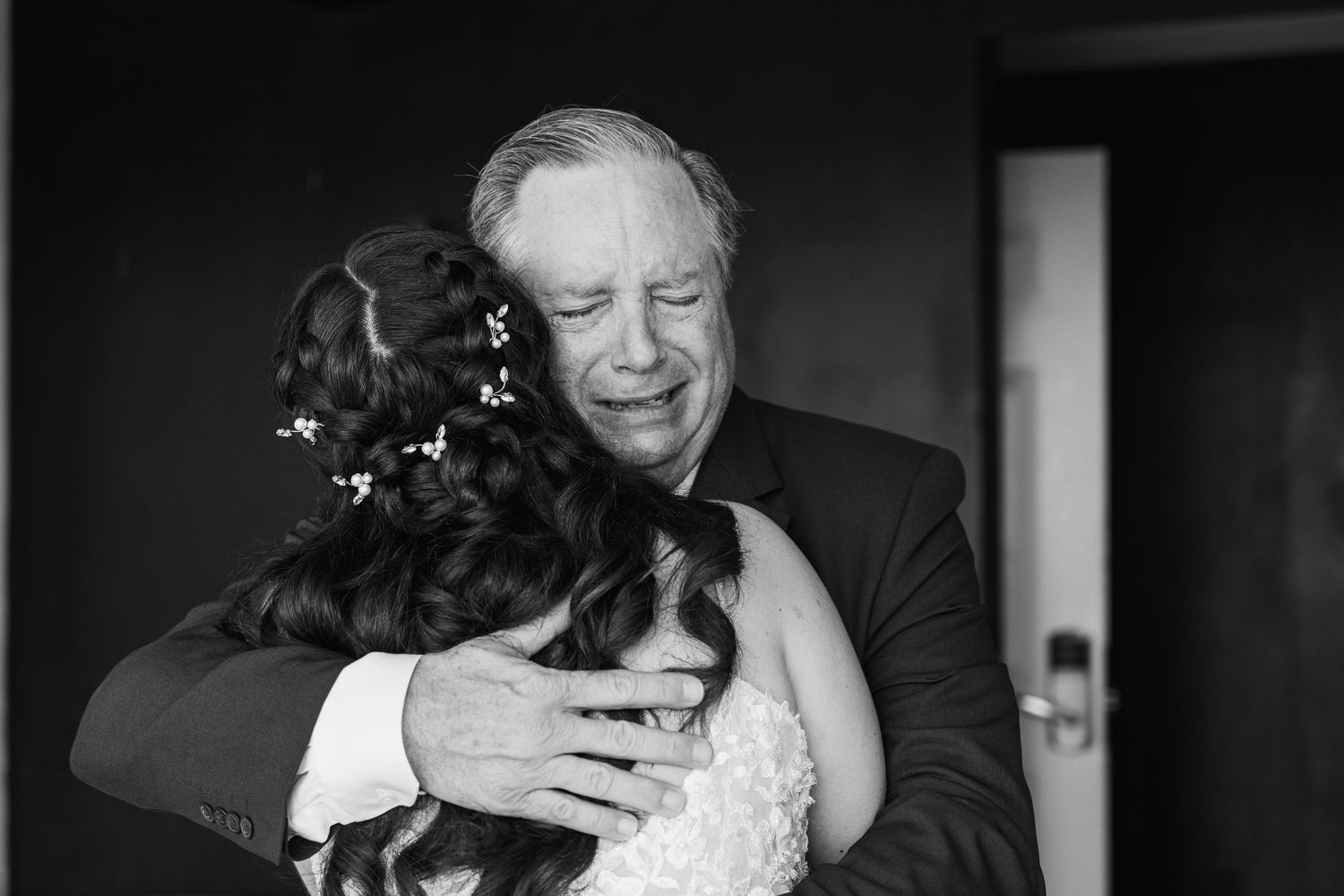Emotional black and white photo of father hugging bride on wedding day.