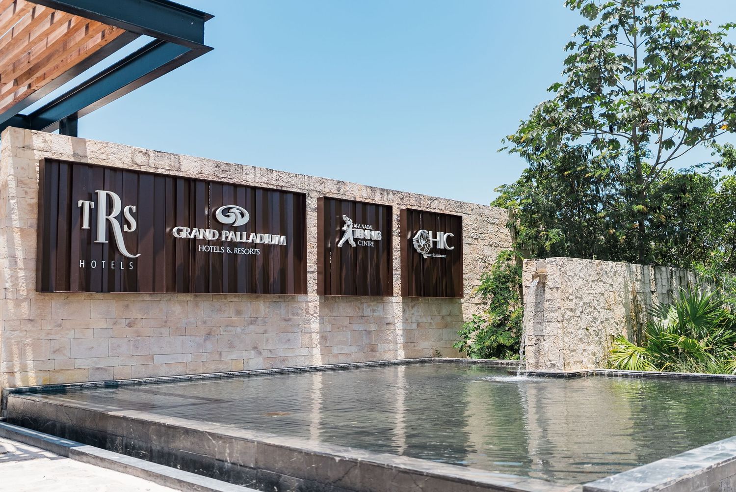 Entrance sign for TRS and Grand Palladium Hotels and Resorts with reflecting pool.