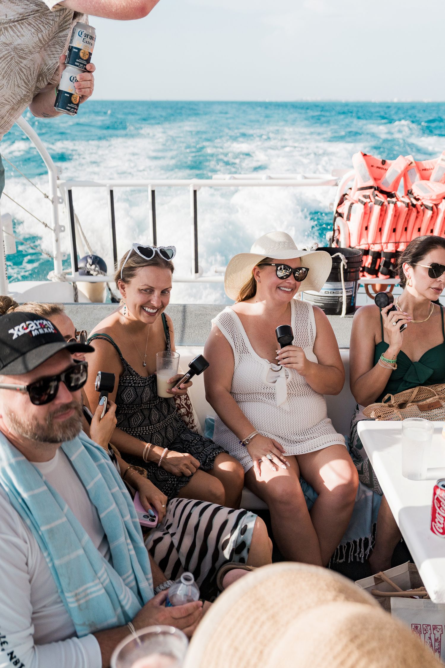 Group of friends enjoying drinks on a boat party in the ocean on a sunny day.