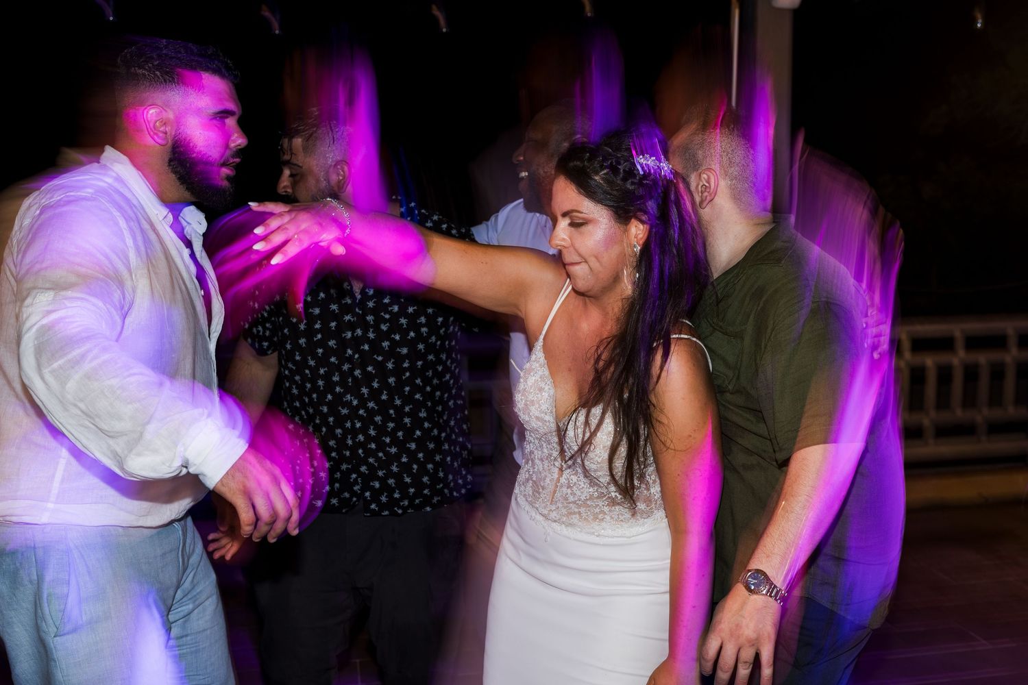 Bride and groom dancing together under purple lights at their wedding reception.