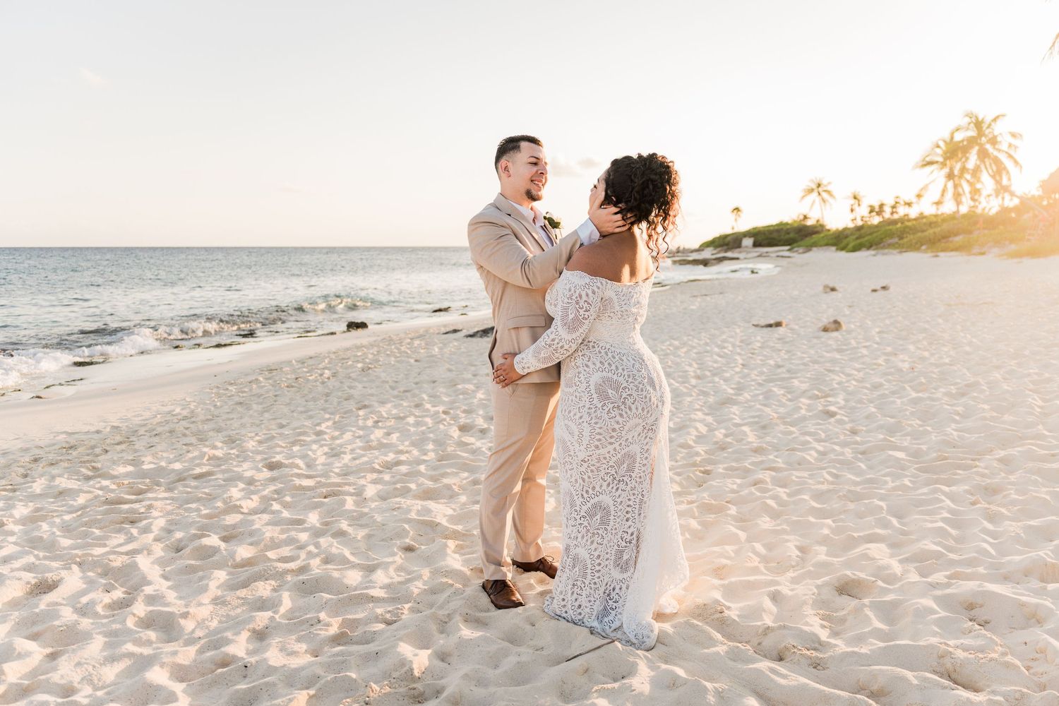 Xcaret Arte Wedding Couple dancing on a sandy beach at sunset, with palm trees and ocean backdrop.