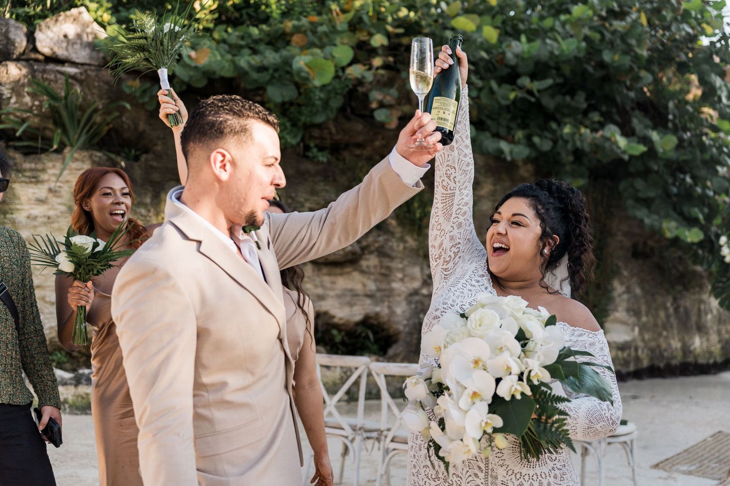 Xcaret Arte Wedding - Joyful interracial couple toasting champagne at outdoor wedding ceremony.