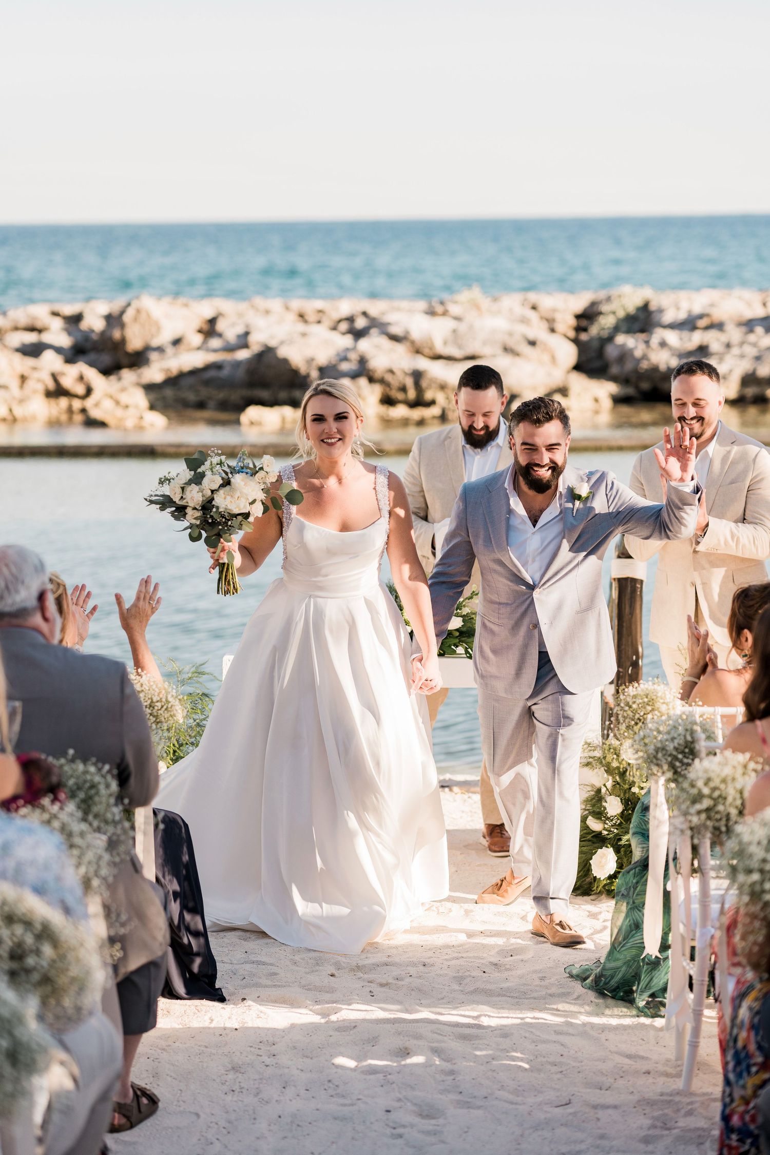 Bride and groom walk down sandy beach aisle after wedding ceremony at Hard Rock Riviera Maya
