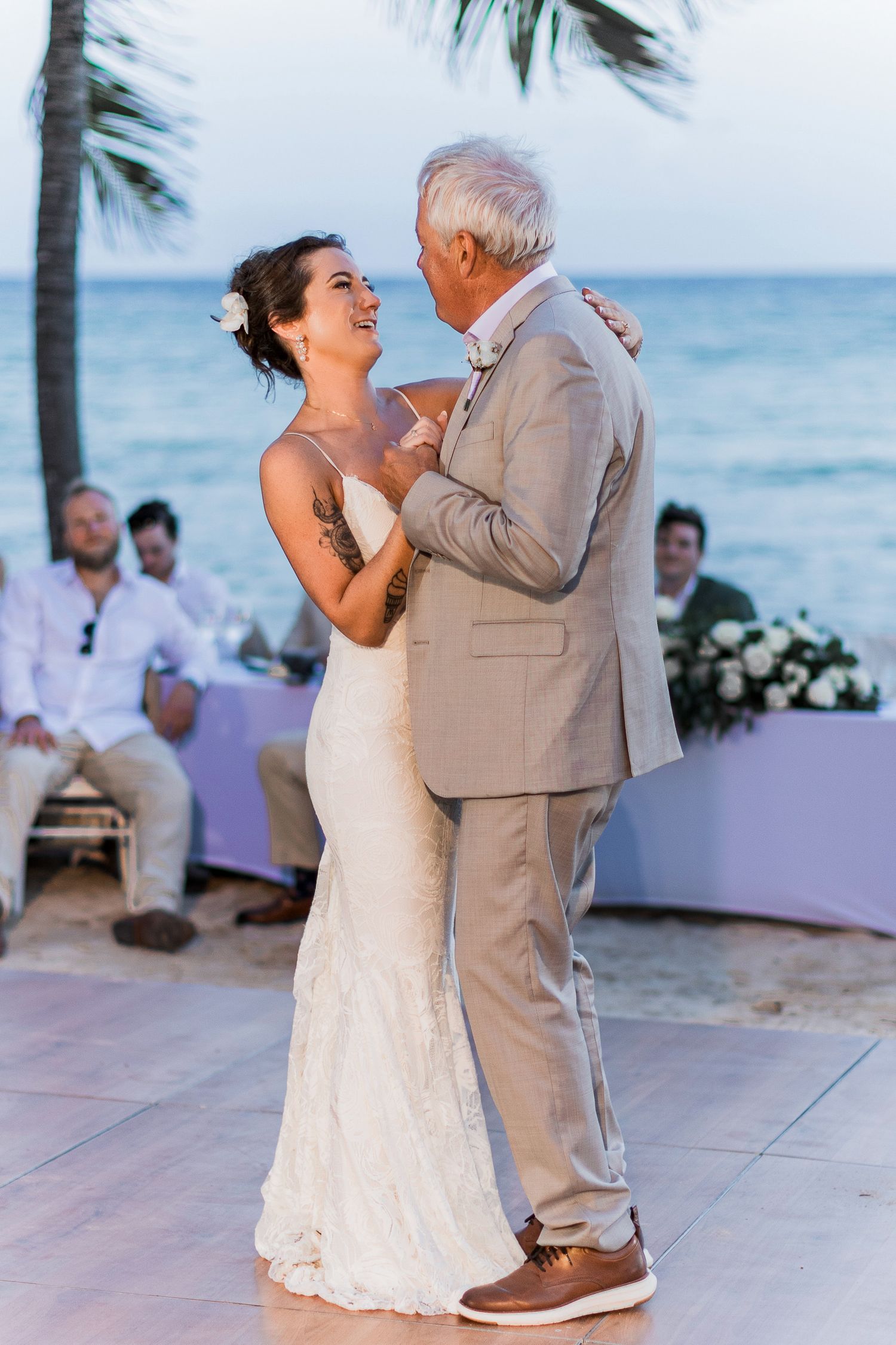 Bride and father share emotional first dance at outdoor beach wedding reception at sunset.