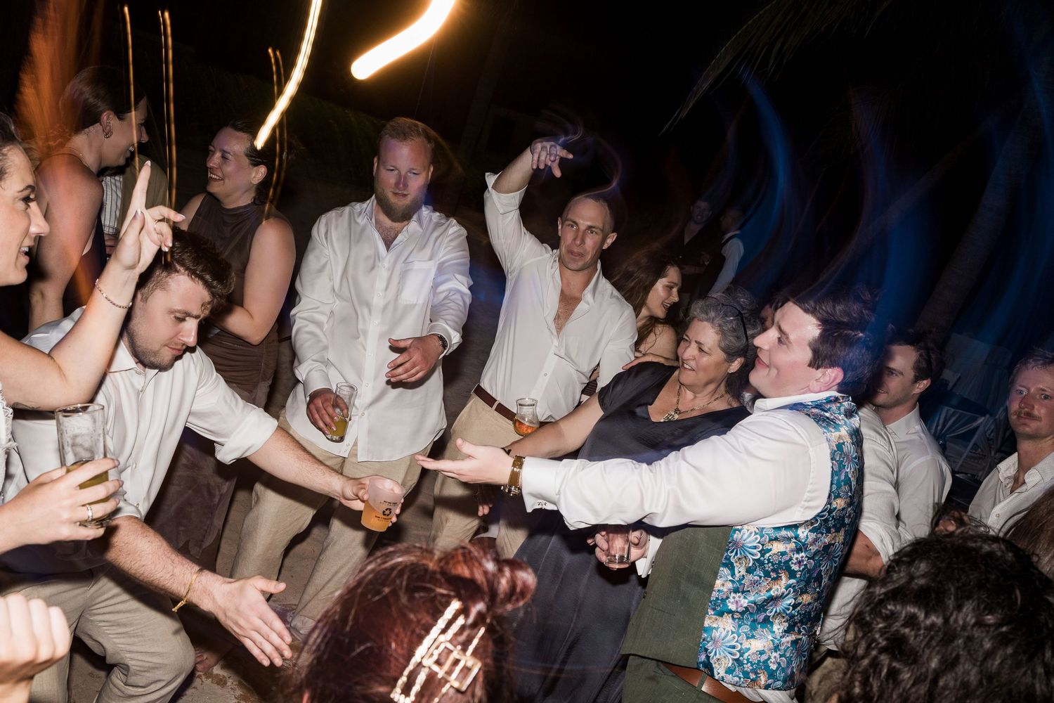 Guests dancing and celebrating at an outdoor evening wedding reception party.