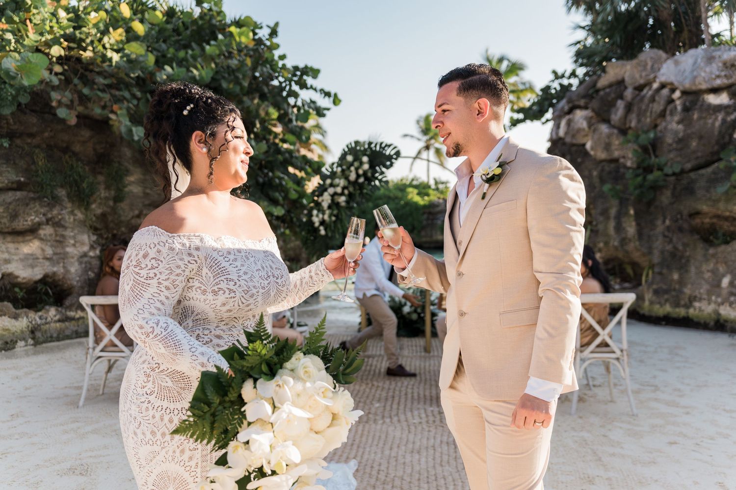 Xcaret Arte Wedding -  Bride and groom toasting with champagne glasses on a sandy beach