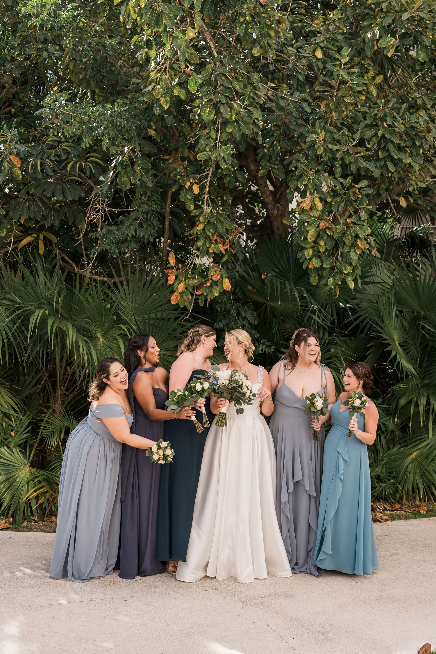 Bride in white gown with five bridesmaids in blue dresses holding bouquets, Hard Rock Riviera Maya wedding