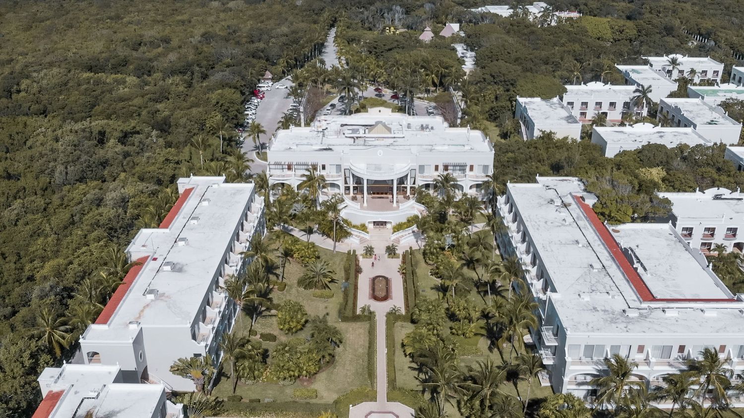Aerial view of a grand white resort surrounded by lush tropical greenery in Mexico.