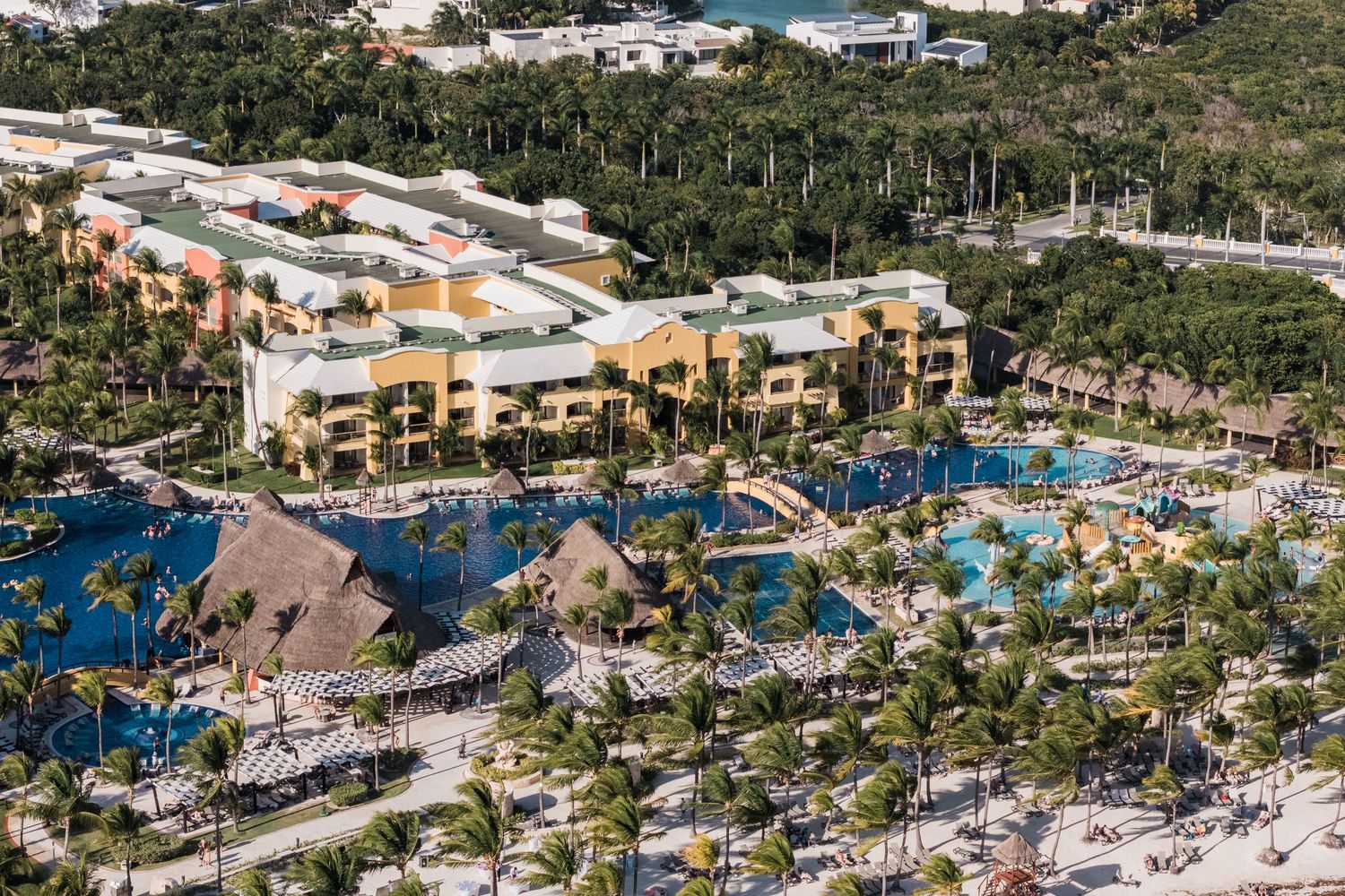 Barcelo Maya Grand Resort Wedding - Aerial view of a tropical resort featuring pools, palm trees, and colorful buildings