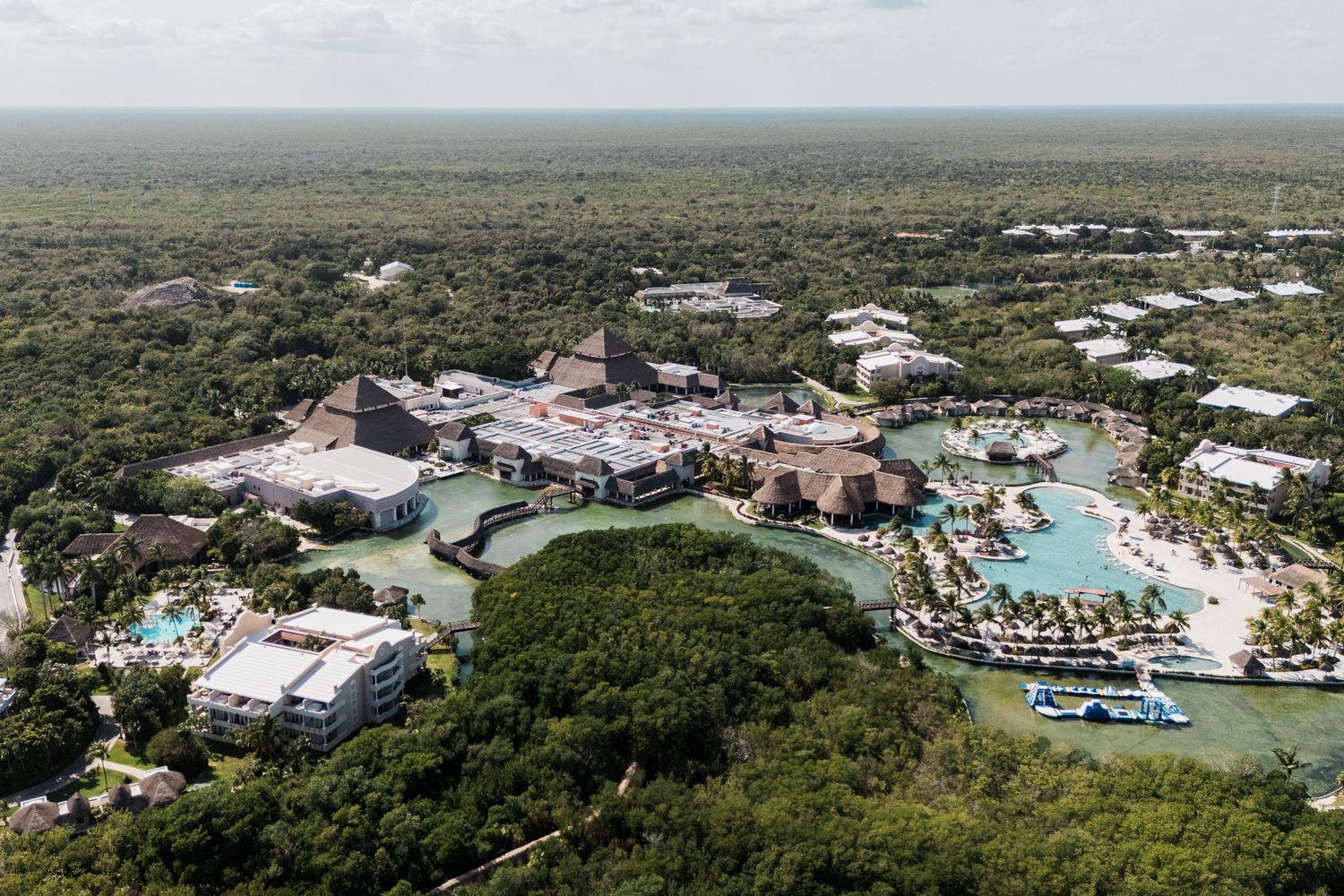 Aerial view of TRS Yucatán Hotel with pools and lagoons surrounded by lush tropical jungle in Mexico.