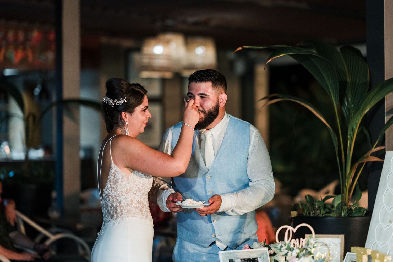 Bride playfully feeds groom a piece of wedding cake during their reception celebration.