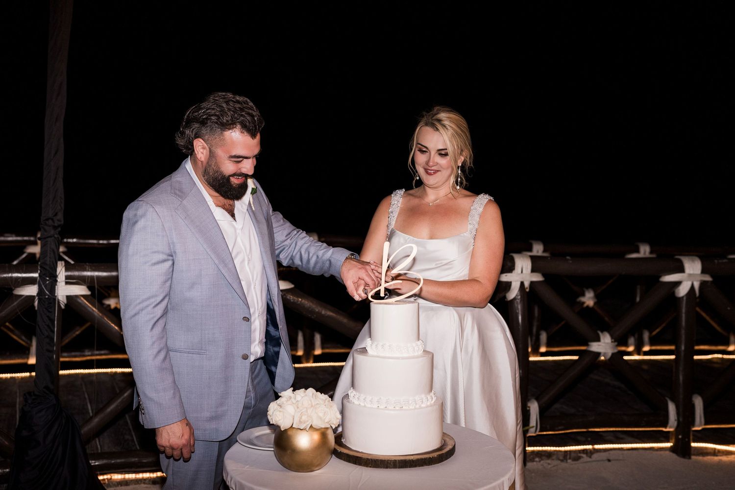 Bride and groom cutting white wedding cake outdoors at Hard Rock Riviera Maya wedding