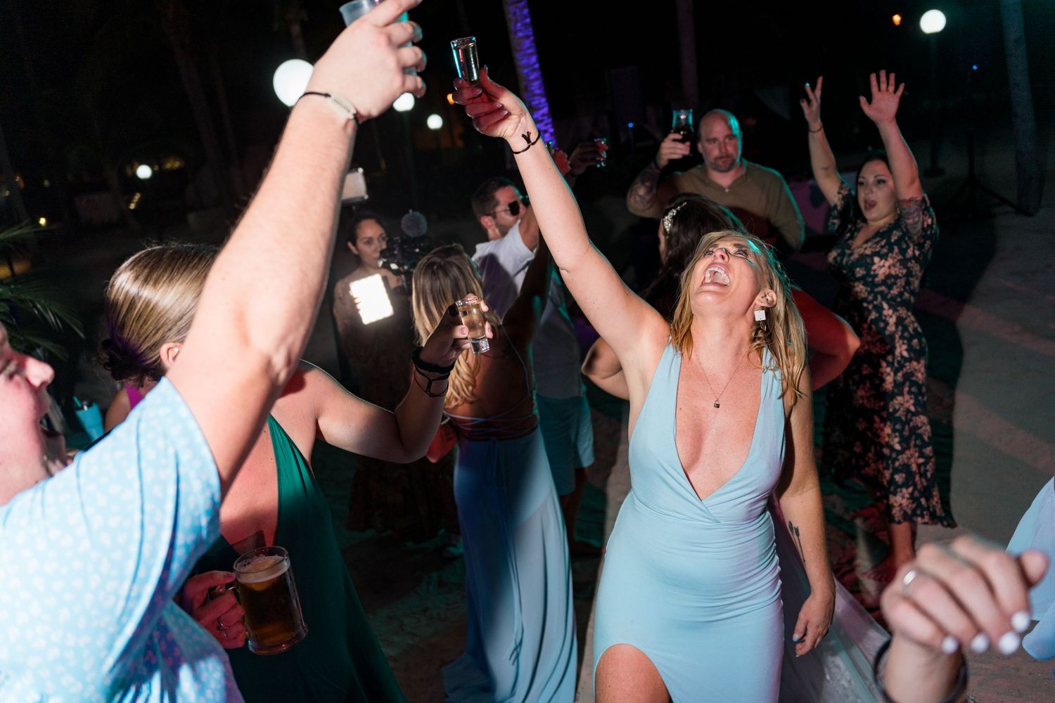Guests dancing and celebrating at a lively outdoor wedding reception at night.