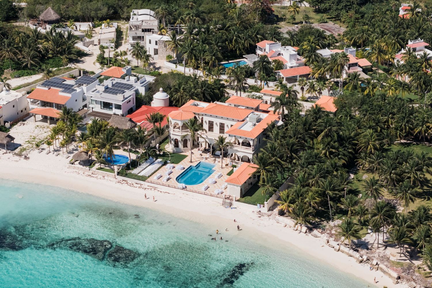Aerial view of luxury beachfront wedding venue with terracotta roofs and turquoise Caribbean water.