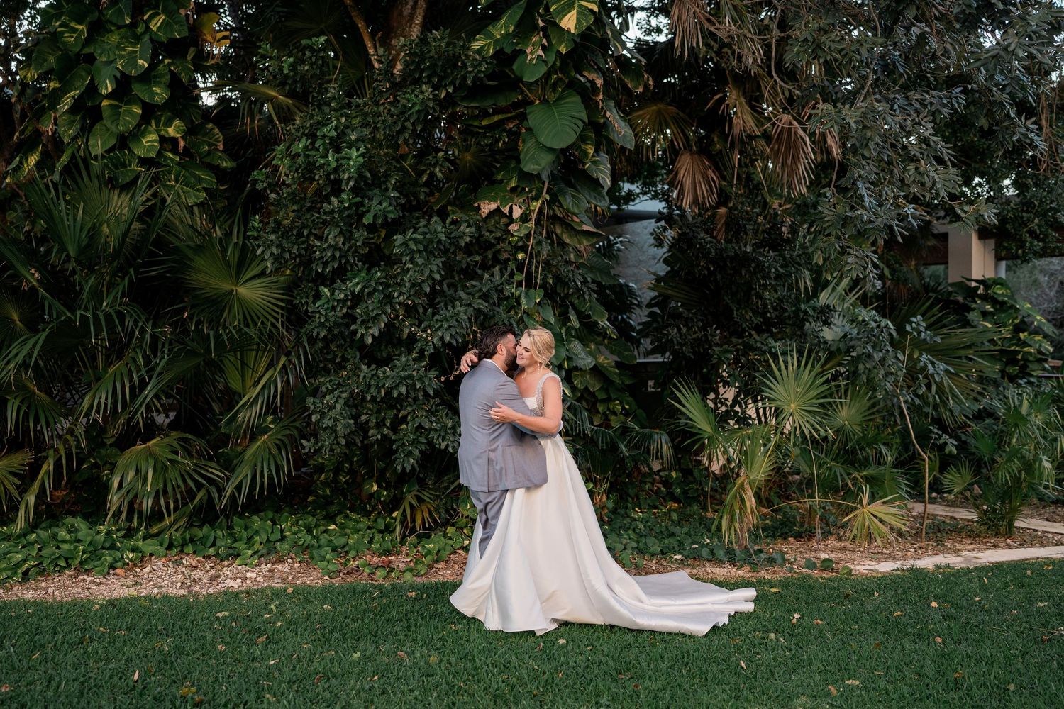 Bride and groom embracing in lush tropical garden, Hard Rock Riviera Maya wedding photographer
