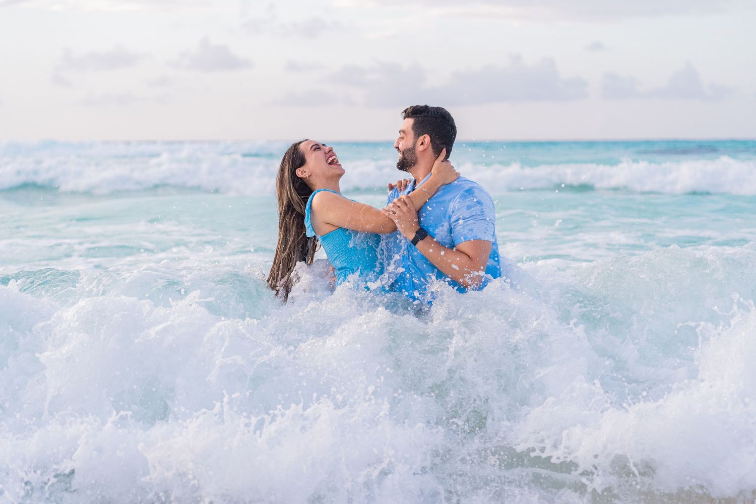 Couple laughing together during beach session in Riviera Maya, they are in the ocean hitter by a wave — Luis Tovilla
