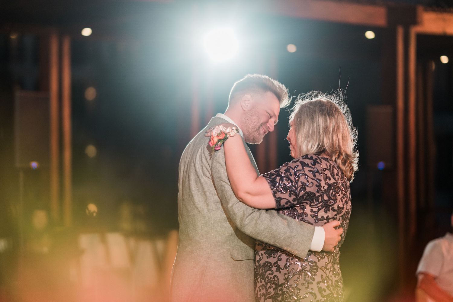 Couple sharing an intimate dance under warm spotlight at an outdoor evening wedding reception.