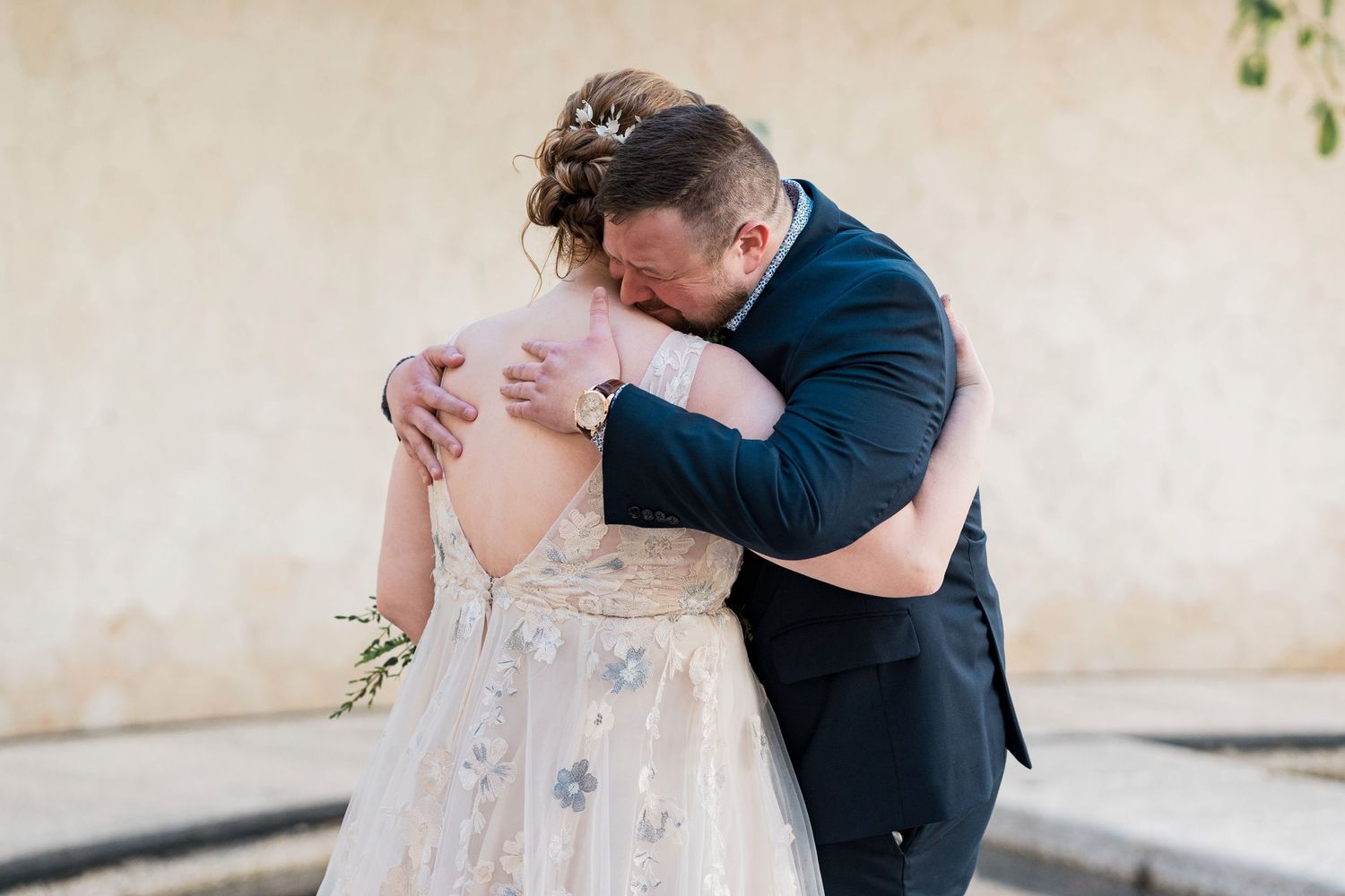 Secrets Akumal Wedding - Bride and groom share an emotional embrace outdoors, wearing elegant wedding attire at their ceremony.