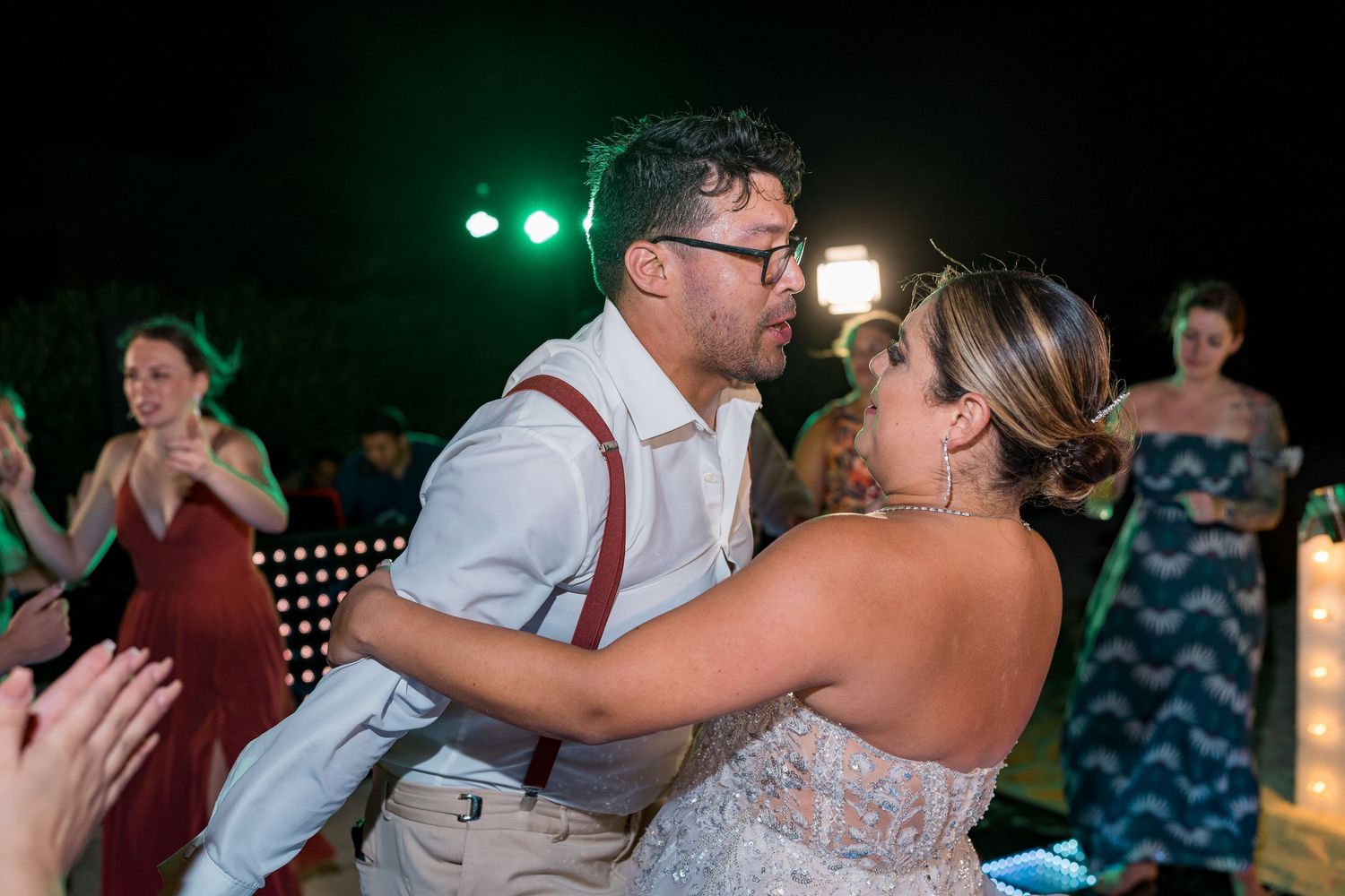 Groomsman in white shirt and suspenders with boutonniere at wedding reception.