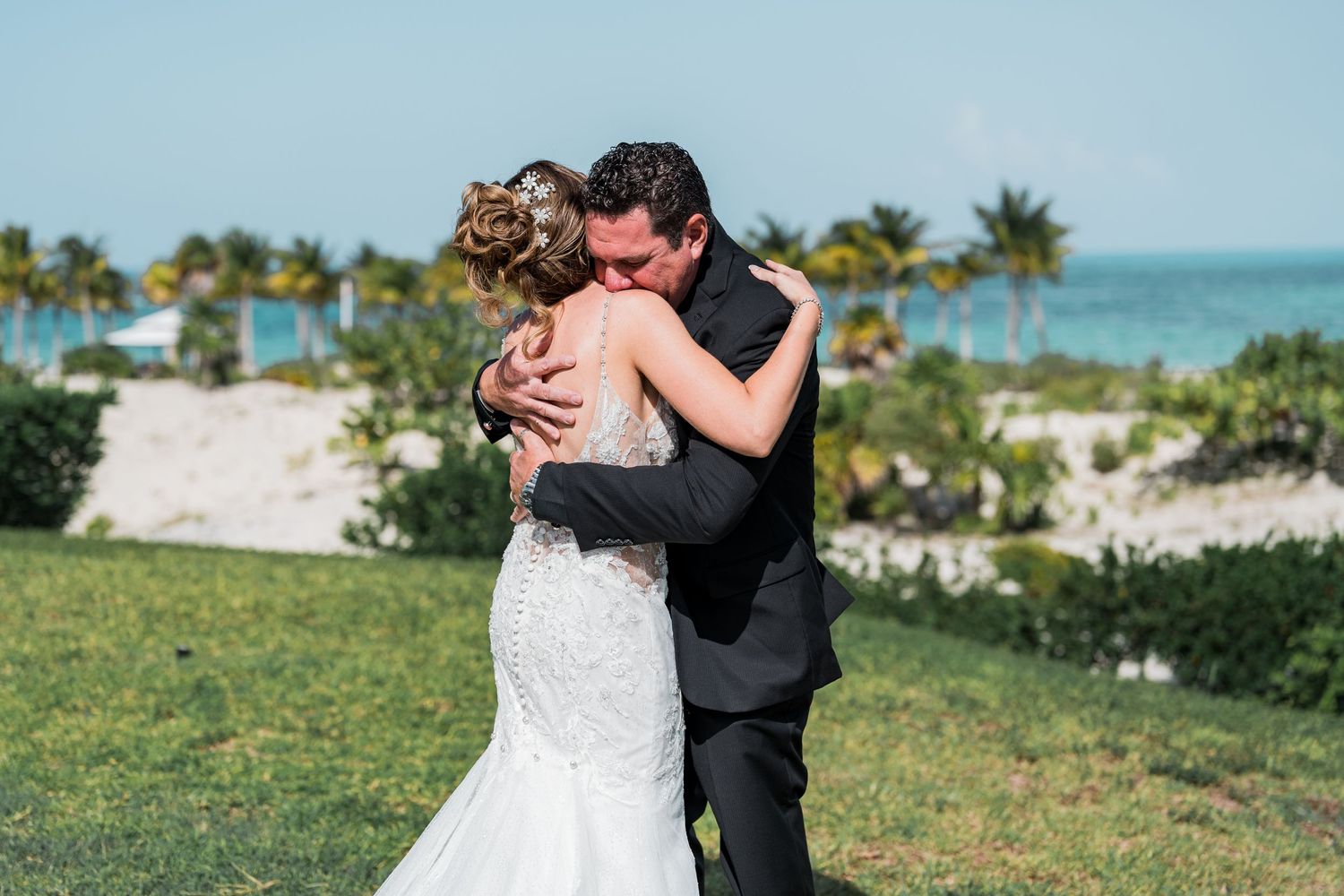 Bride and groom sharing emotional embrace during first look by the ocean.
