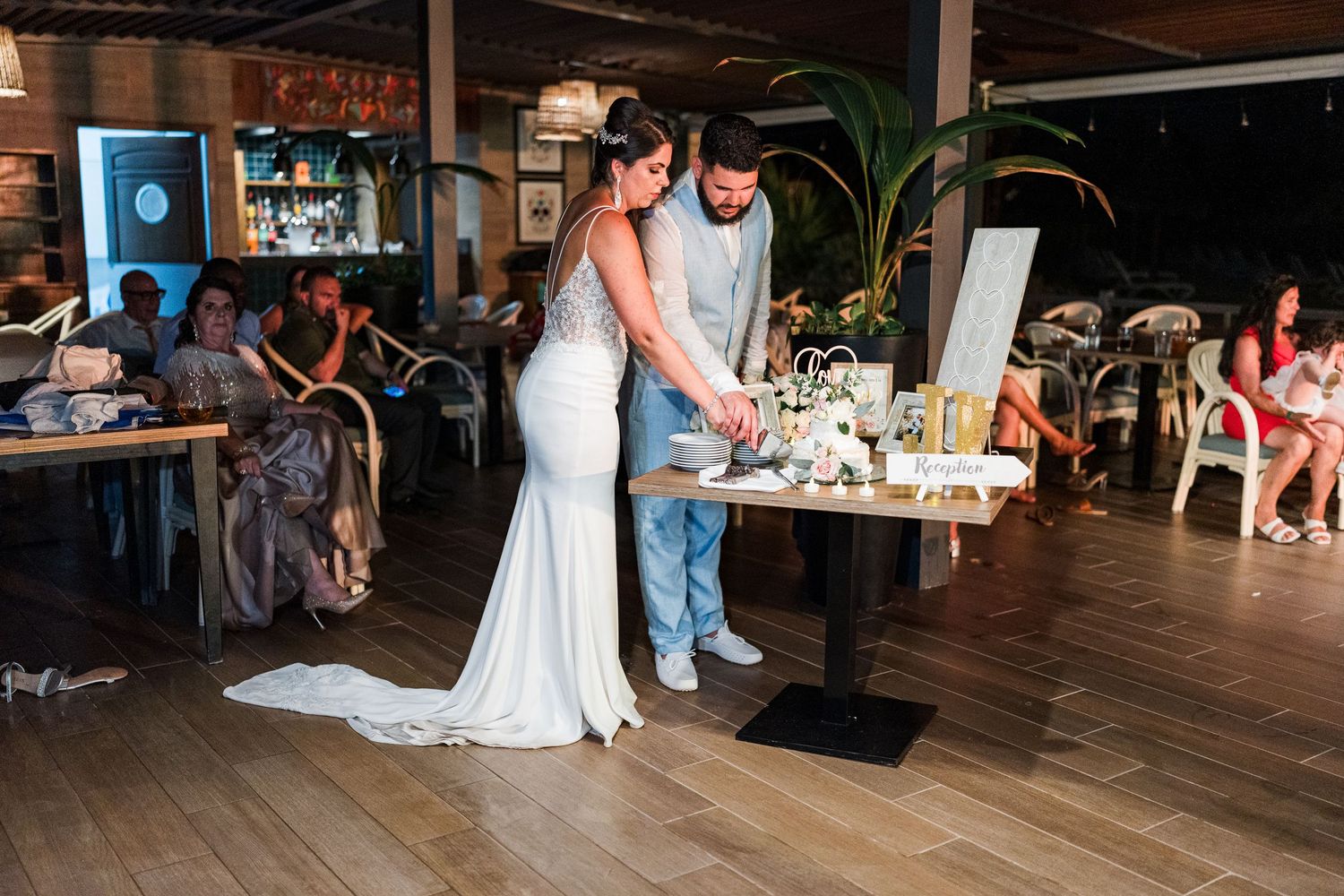 Bride and groom cutting their wedding cake at an elegant indoor reception venue.