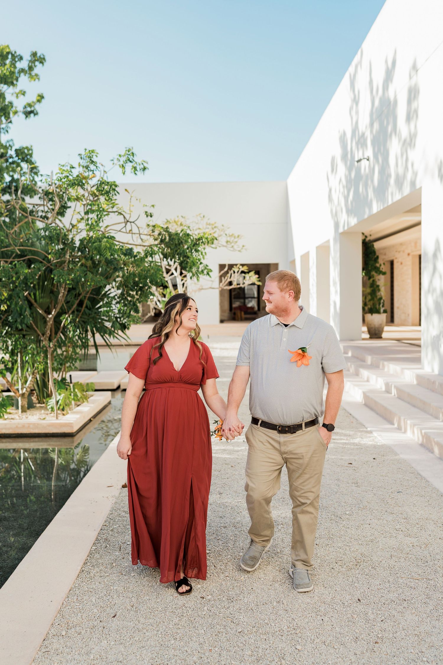 Secrets Akumal Wedding - Couple holding hands and walking together outdoors near a reflective pool