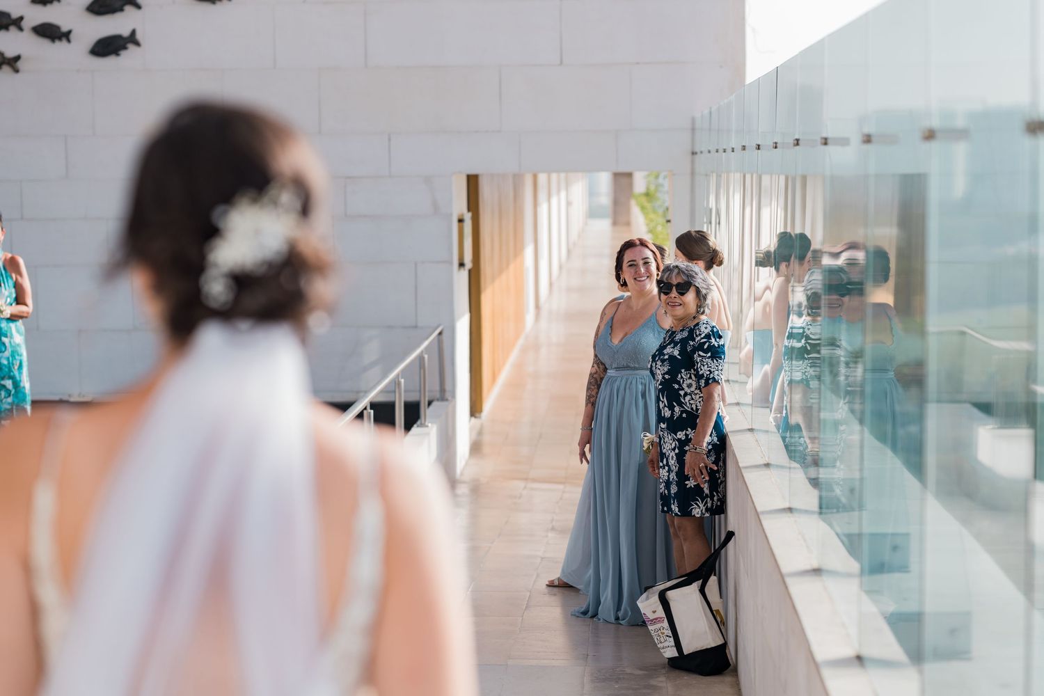 Bridesmaids in dusty blue gowns react emotionally as bride approaches during outdoor wedding first look.