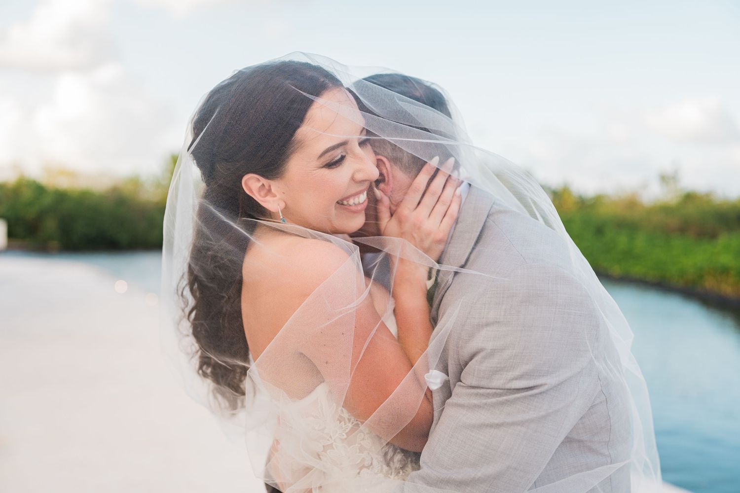 Bride and groom share an intimate moment under a flowing white veil on a tropical beach wedding day. grand palladium costa mujeres wedding