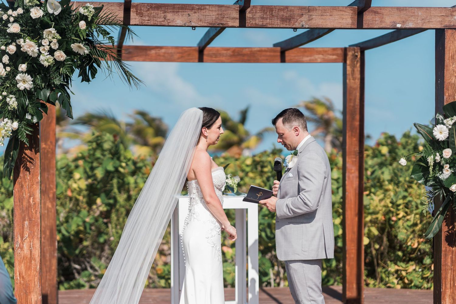 Couple exchanging vows at outdoor wedding altar at grand palladium costa mujeres wedding