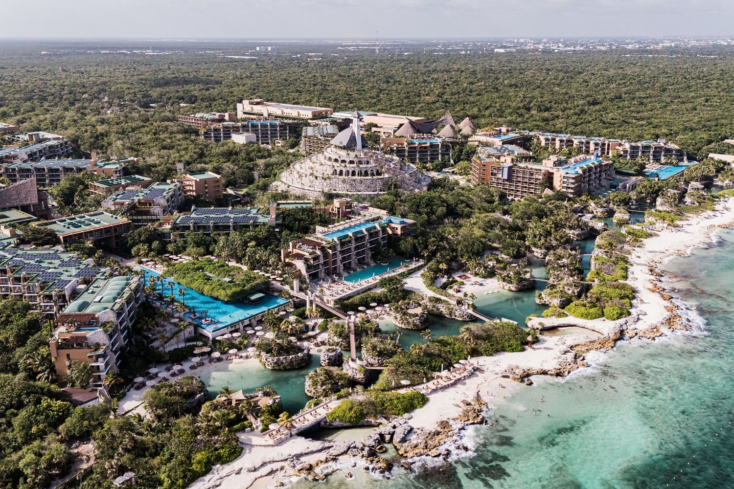 Hotel Xcaret México Wedding  - Aerial view of a luxury beachfront resort nestled among lush tropical jungle with turquoise Caribbean waters.