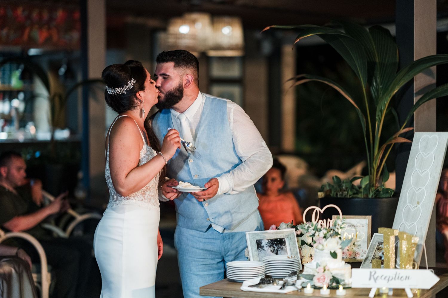 Bride and groom sharing a kiss while holding a microphone during their wedding reception speech.