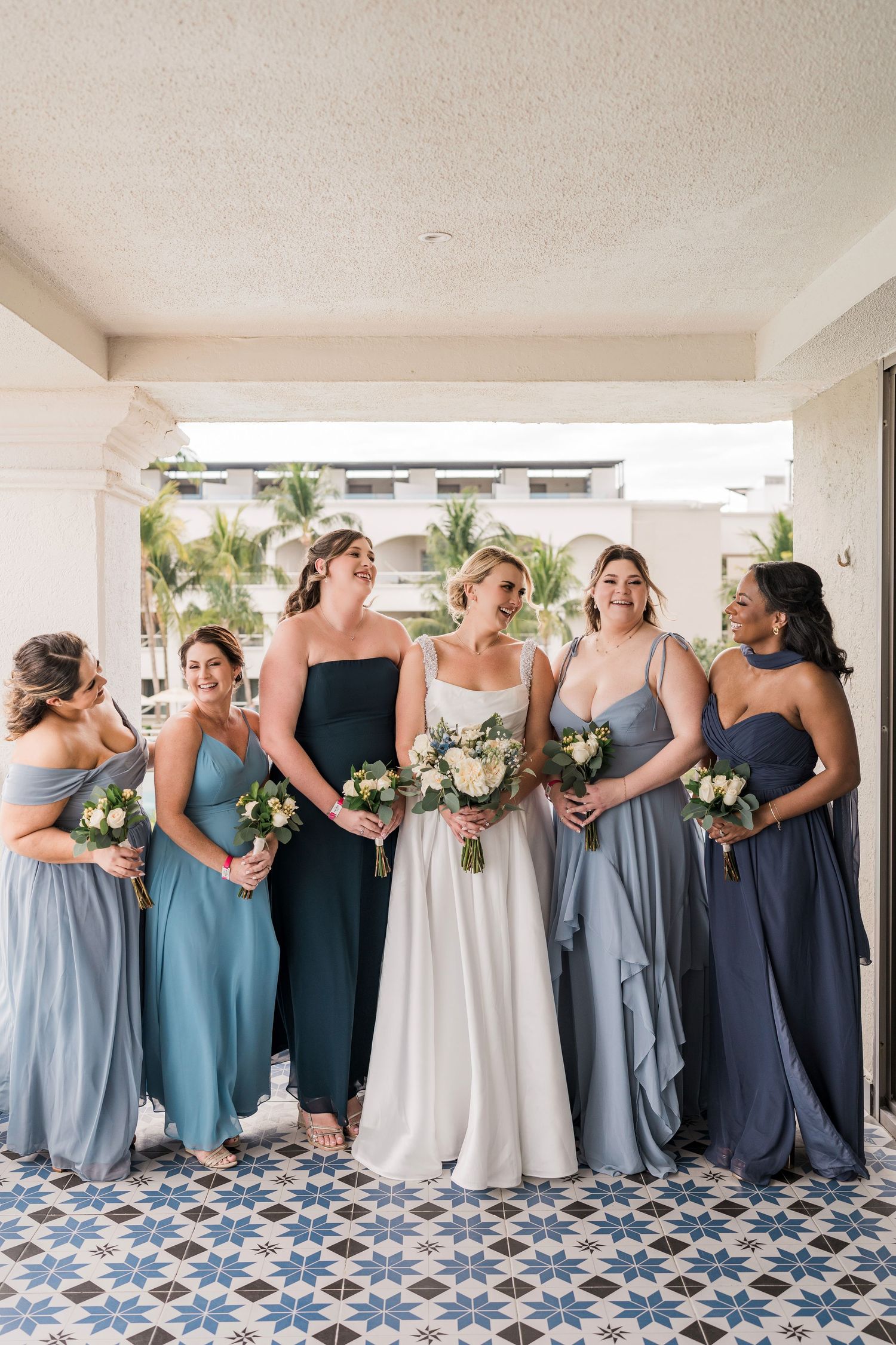 Bride in white gown with bridesmaids in blue dresses holding bouquets, Hard Rock Riviera Maya wedding