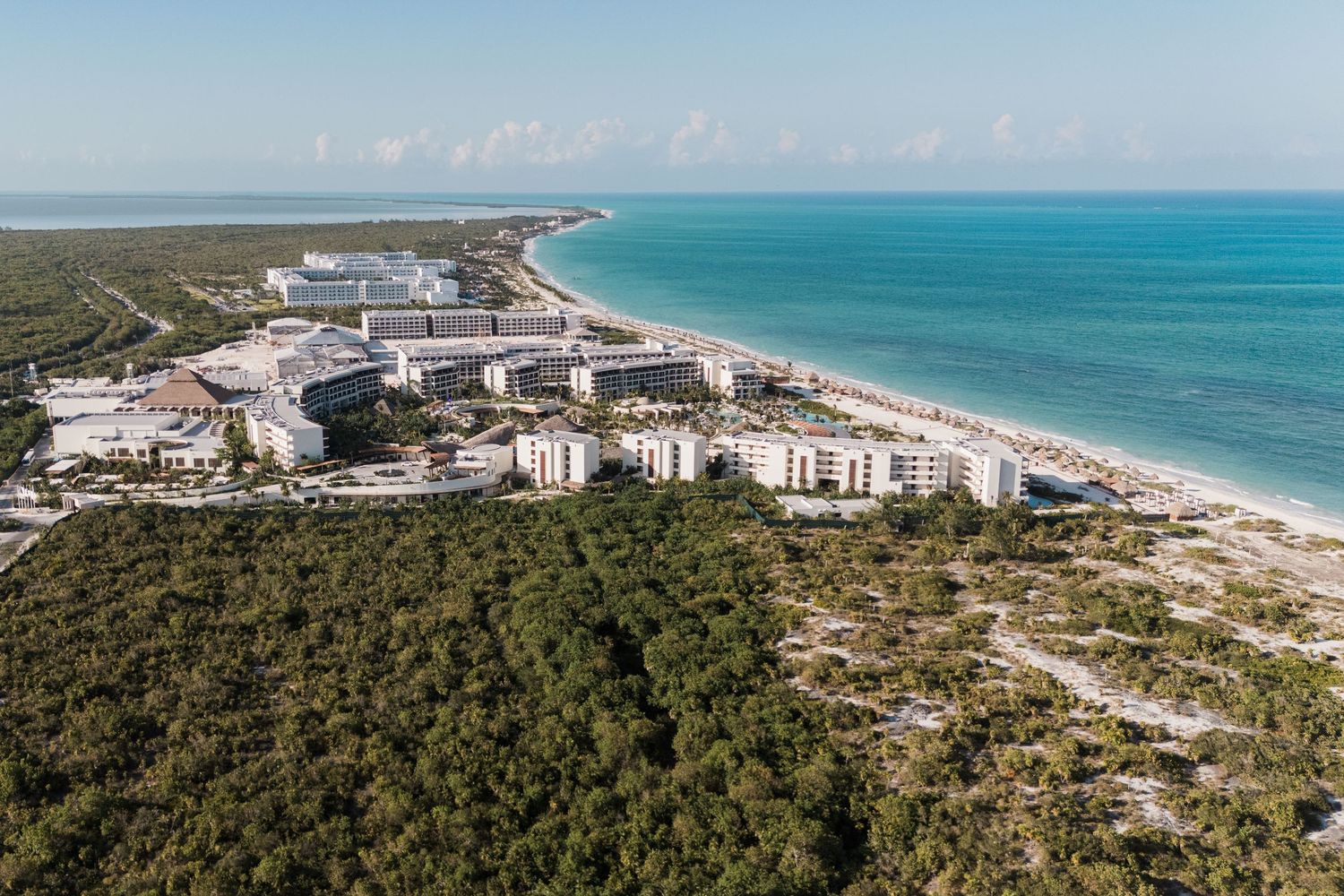 Aerial view of a beachfront luxury resort surrounded by lush greenery and turquoise Caribbean waters.