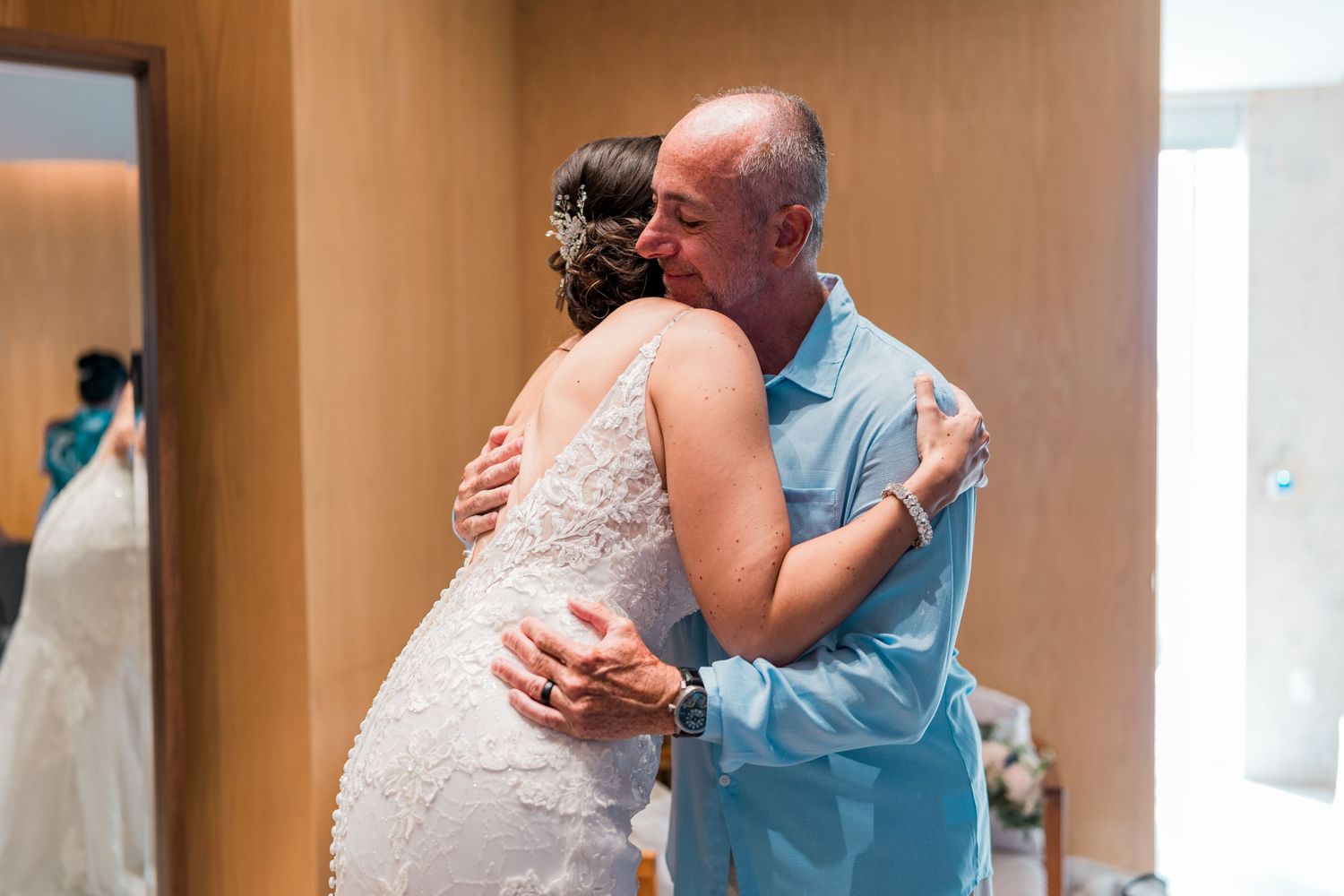 Father embraces bride in heartfelt hug during wedding day first look moment.