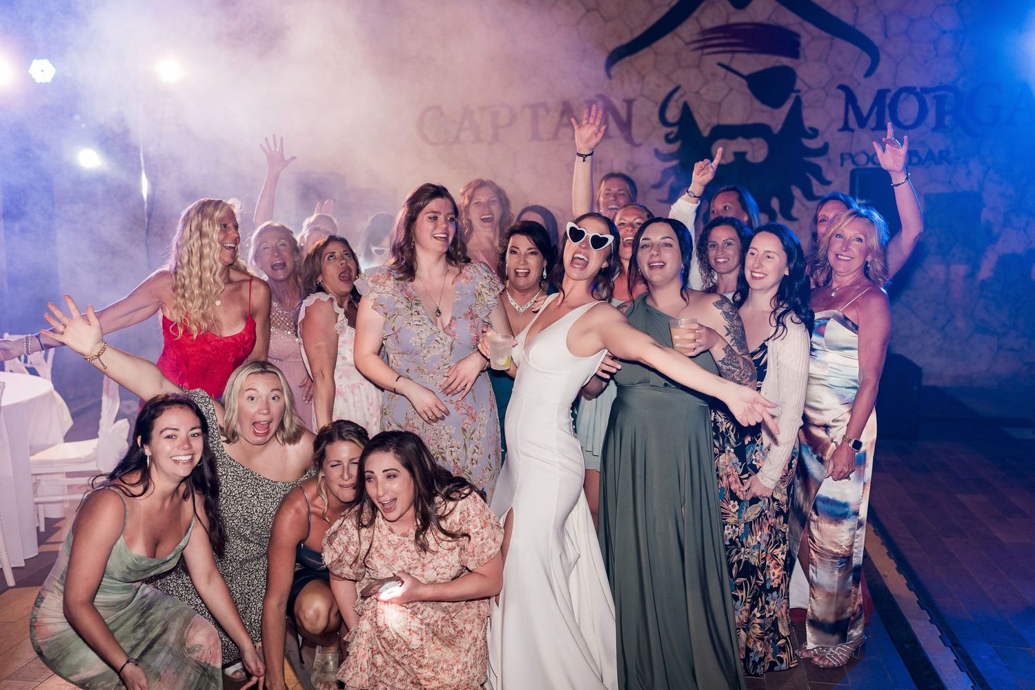 A bride celebrates with a group of women at a Captain Morgan themed wedding reception party.
