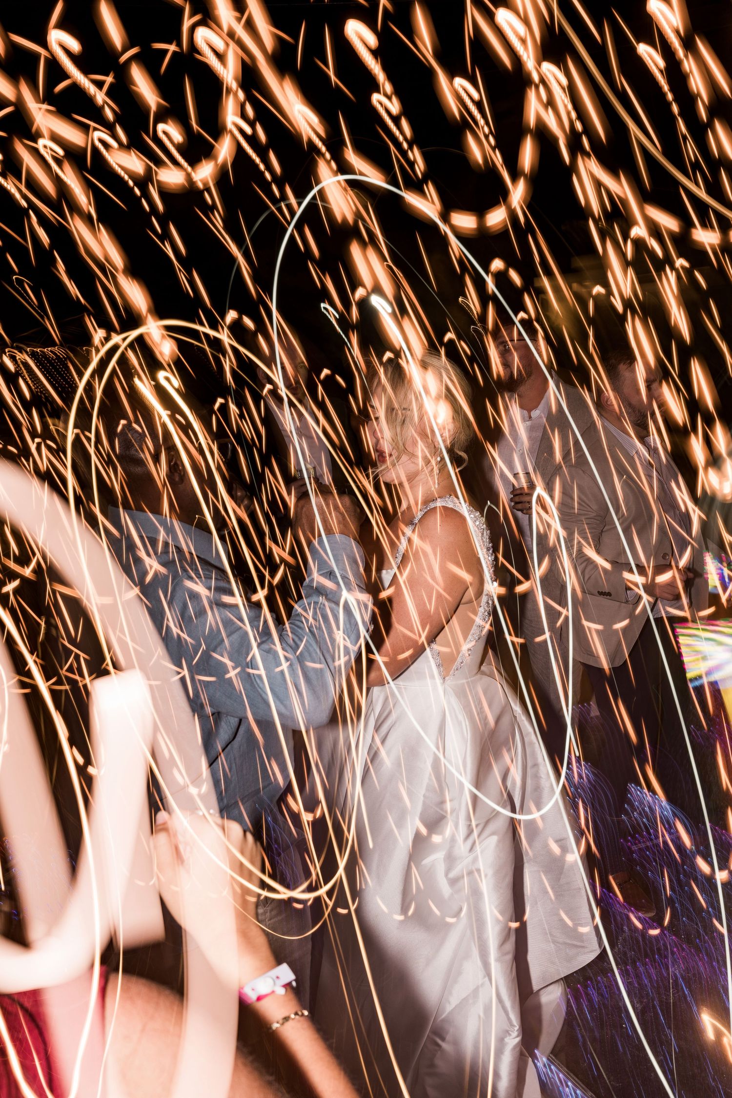 Bride and groom dancing surrounded by sparkling fireworks and light trails at a wedding celebration. Hard Rock Riviera Maya wedding