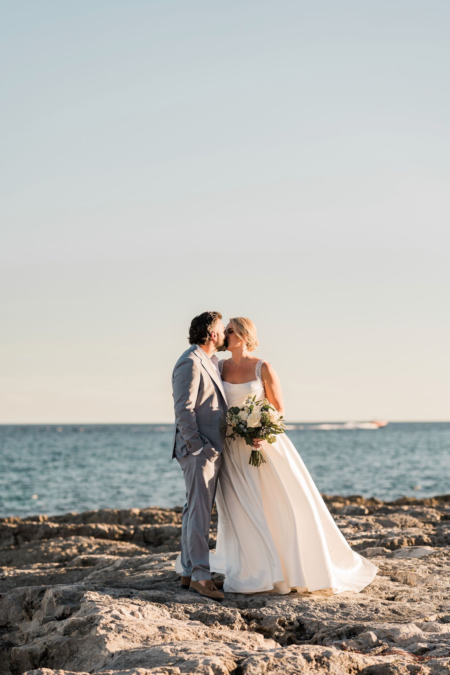 Bride and groom share a romantic moment on rocky shore at a Hard Rock Riviera Maya wedding