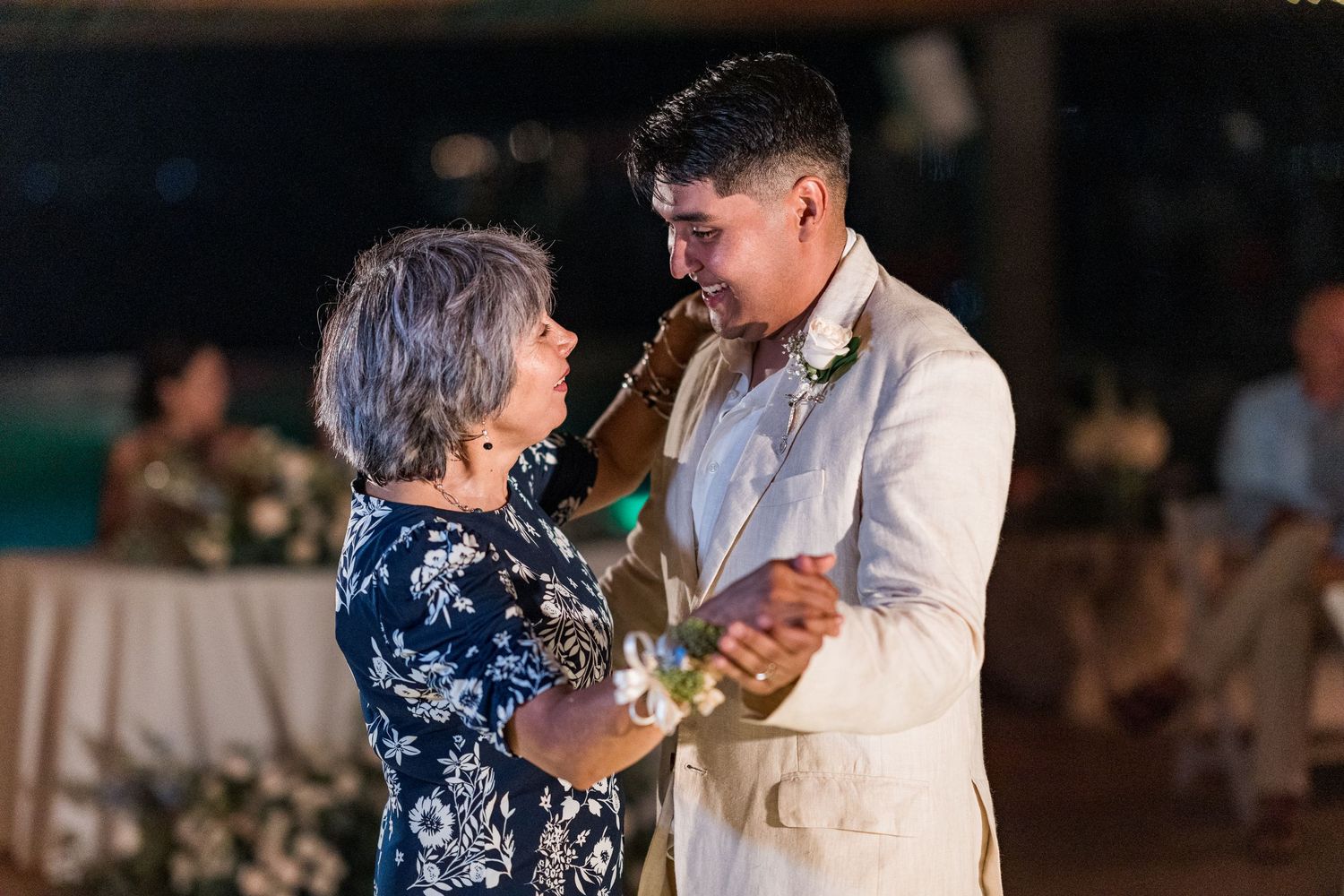 Groom shares a tender mother-son dance at an elegant outdoor evening wedding reception.