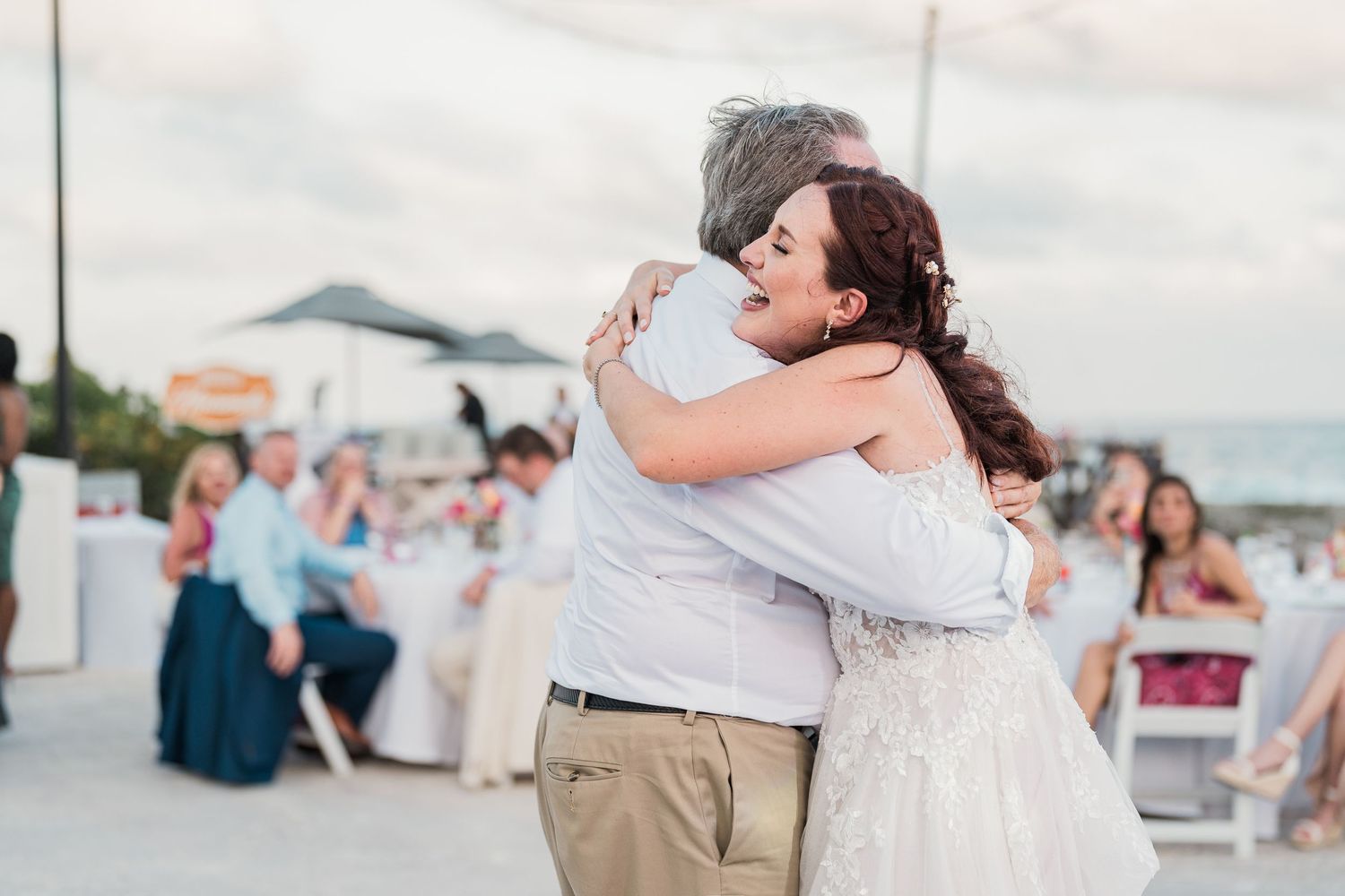 Bride shares an emotional hug with a family member during a heartfelt moment at her outdoor wedding reception.