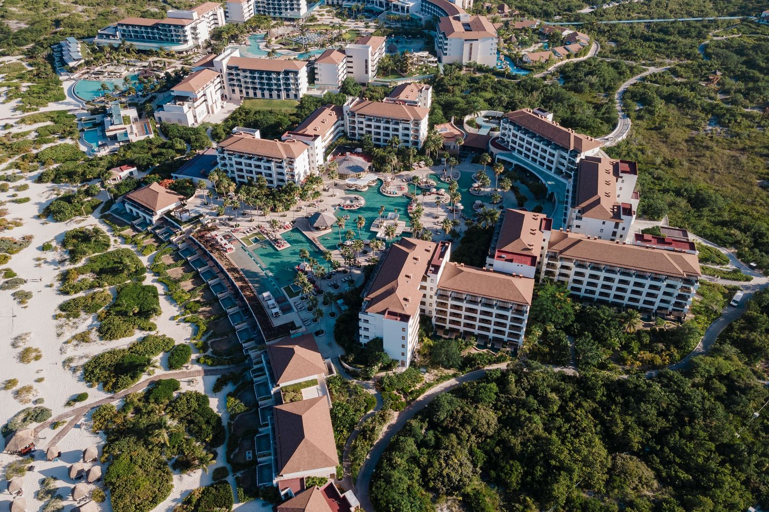 Aerial view of large luxury resort complex with pools surrounded by lush tropical vegetation.