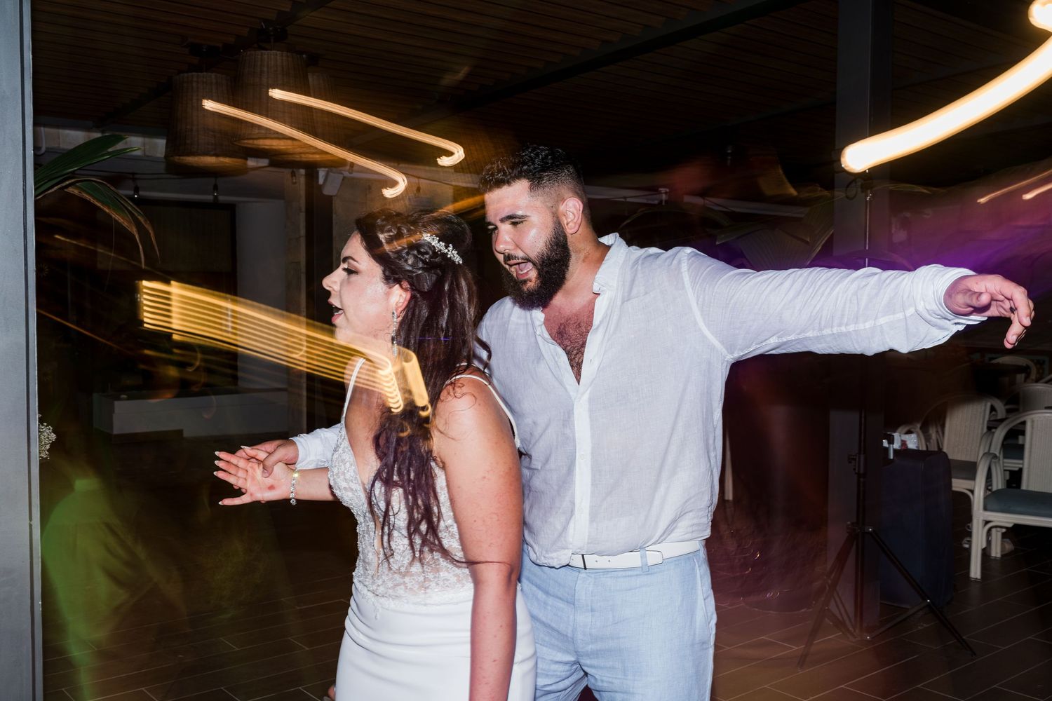 Bride and groom share a lively first dance at their wedding reception under warm glowing lights.
