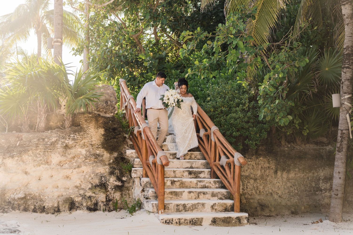 Xcaret Arte Wedding - Bride and groom descend wooden staircase on tropical beach