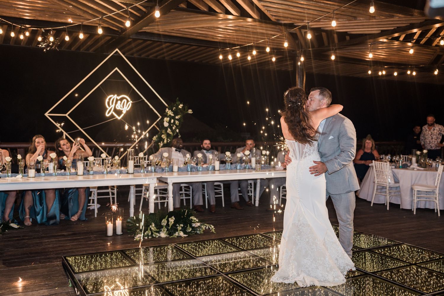 Couple shares first dance on mirrored floor at elegant outdoor wedding reception, grand palladium costa mujeres wedding.